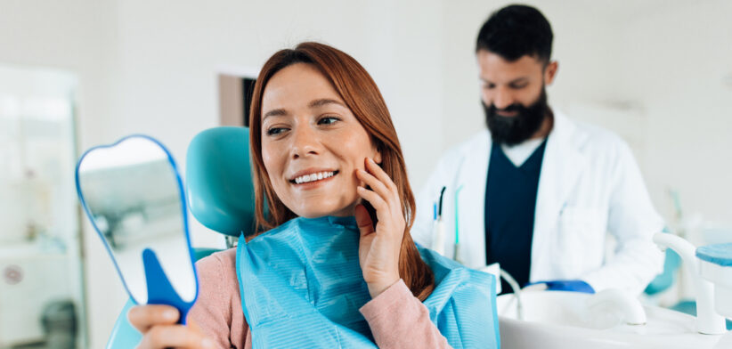 Woman admiring her smile after dental checkup at the dentist’s office