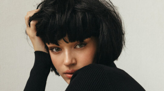 Portrait of a young woman with short black hair in a black knit sweater, conveying introspection